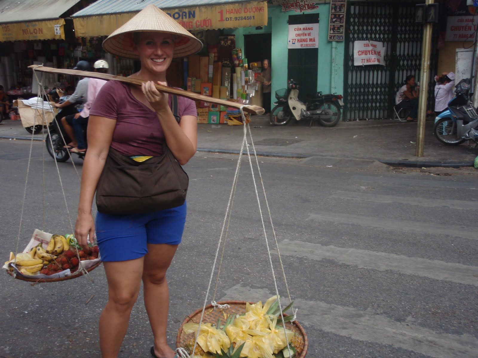 Female tourist posing with market goods wearing a nón lá