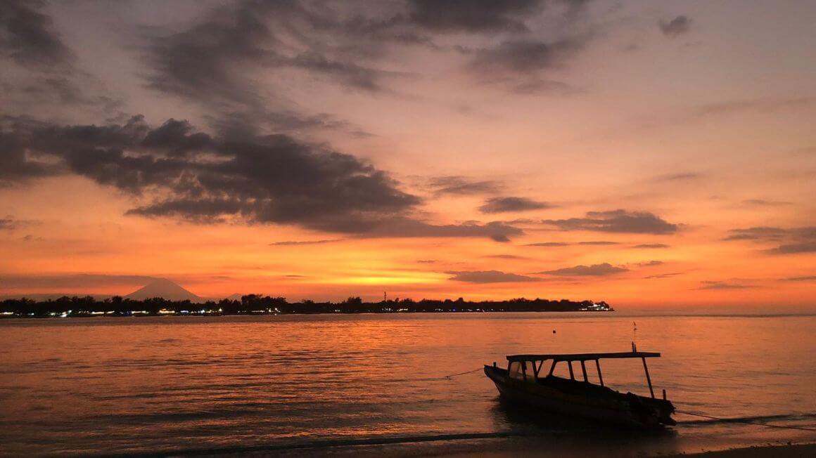 sunset on the beach with a boat in the gili islands, indonesia