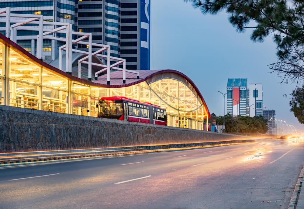 public transportation in pakistan red bus pulling into station