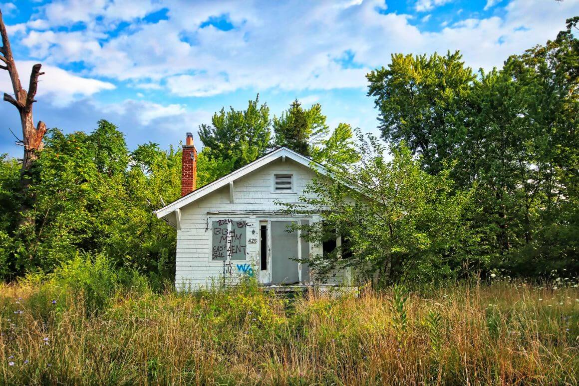 white abandoned house in overgrown yard detroit travel guide