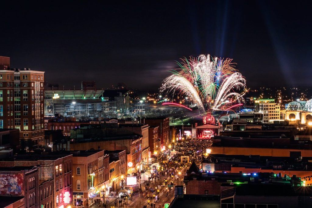fireworks exploding over downtown nashville as a crowd packs the street
