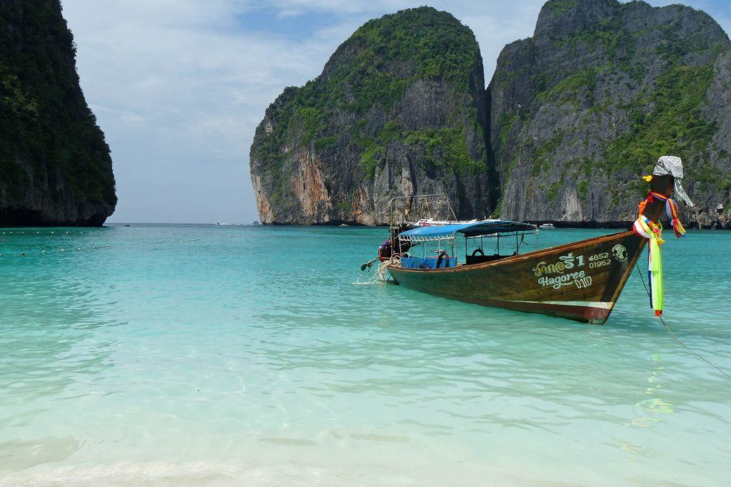 A boat floating on the ocean with rocky formations in the background in Koh Phi Phi, Krabi