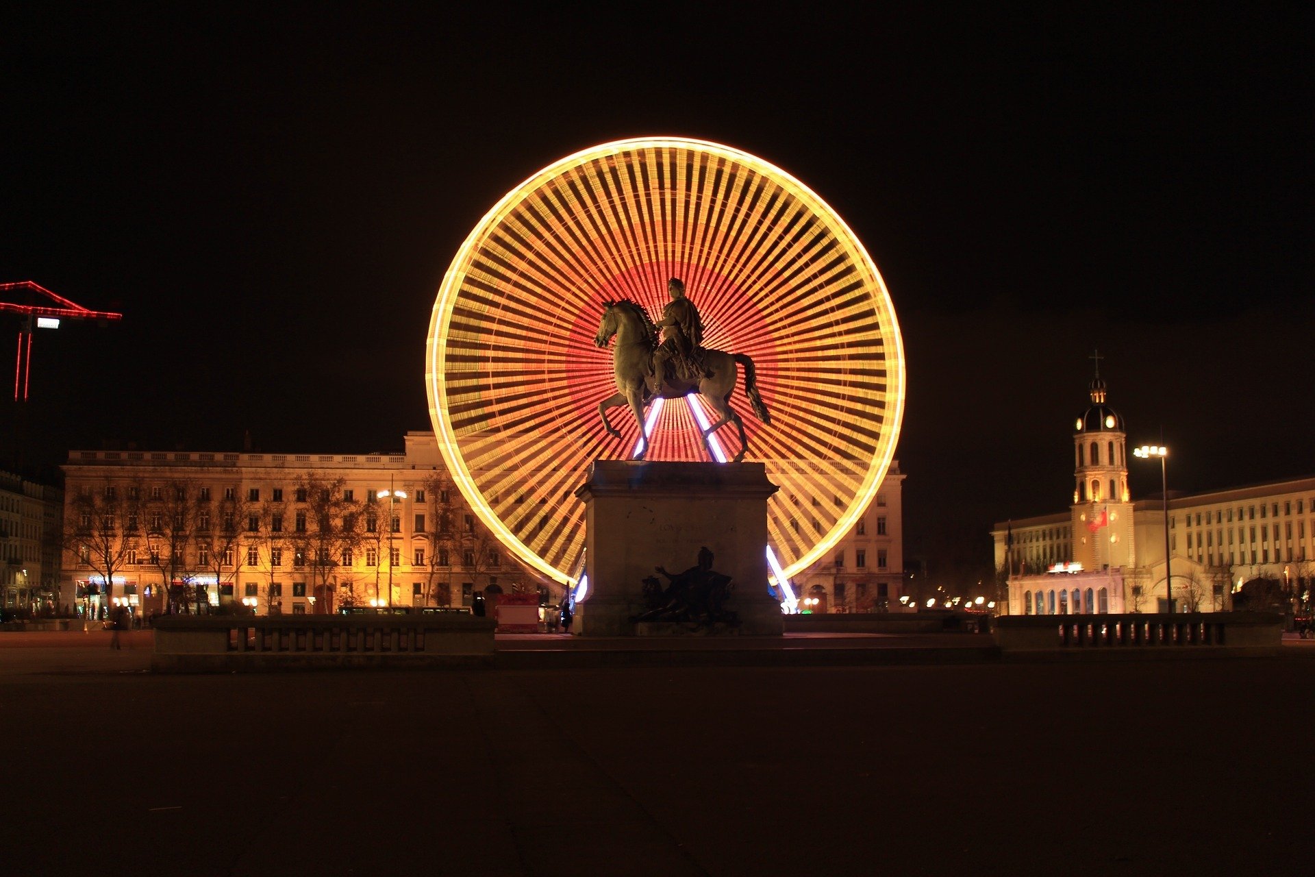 Night time shot of lit up ferris wheel and statue in La Presqu'Ile, Lyon