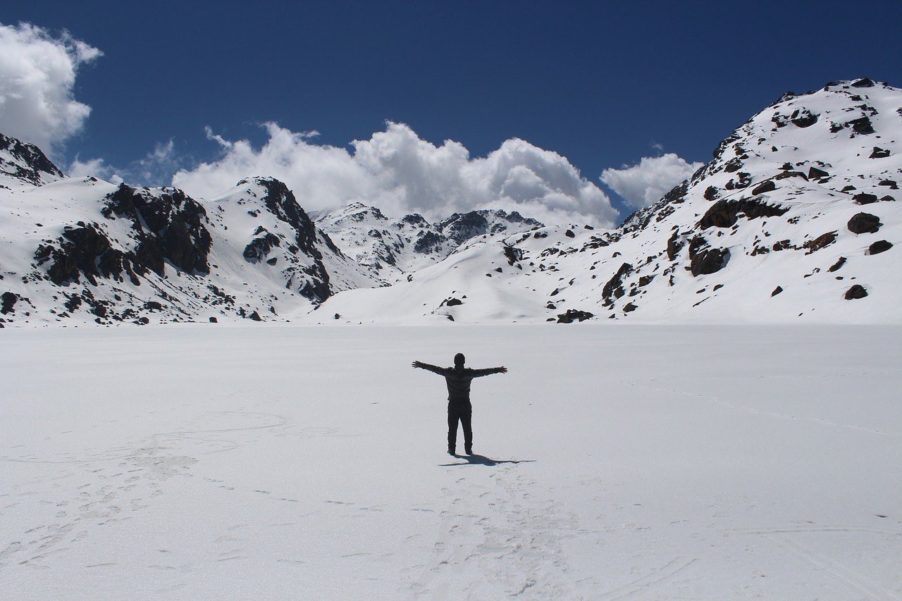 Solo traveller in Nepal standing in a snowfield celebrating his arrival