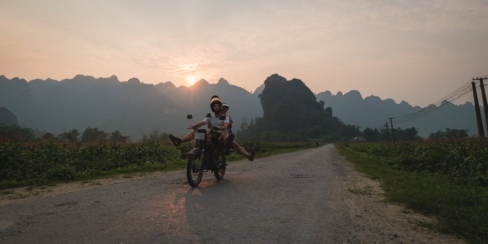 Two tourists travelling Vietnam by motorbike on a rural road