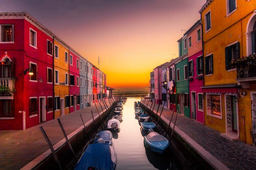 boats lining in a canal surrounded by colorful buildings in Burano Island