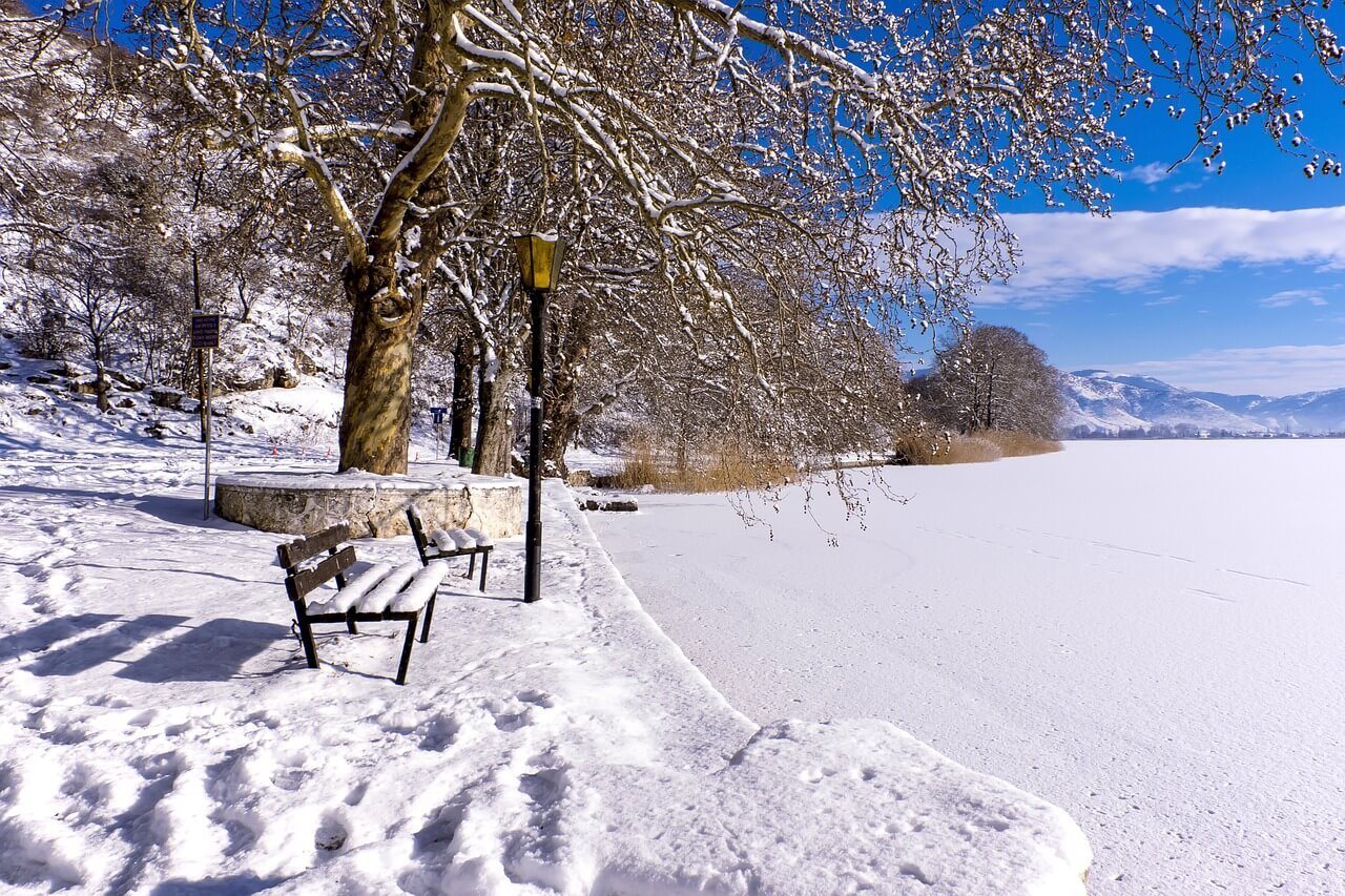 A snowy bench in a park in winter in Greece