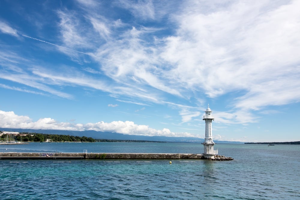 Blue skies with wispy clouds over the still crystal clear waters of Lake Geneva, Paquis, Geneva