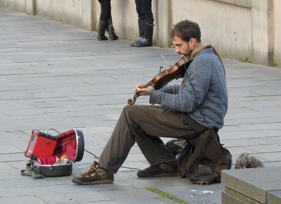 Solo man with a violin wondering where to busk