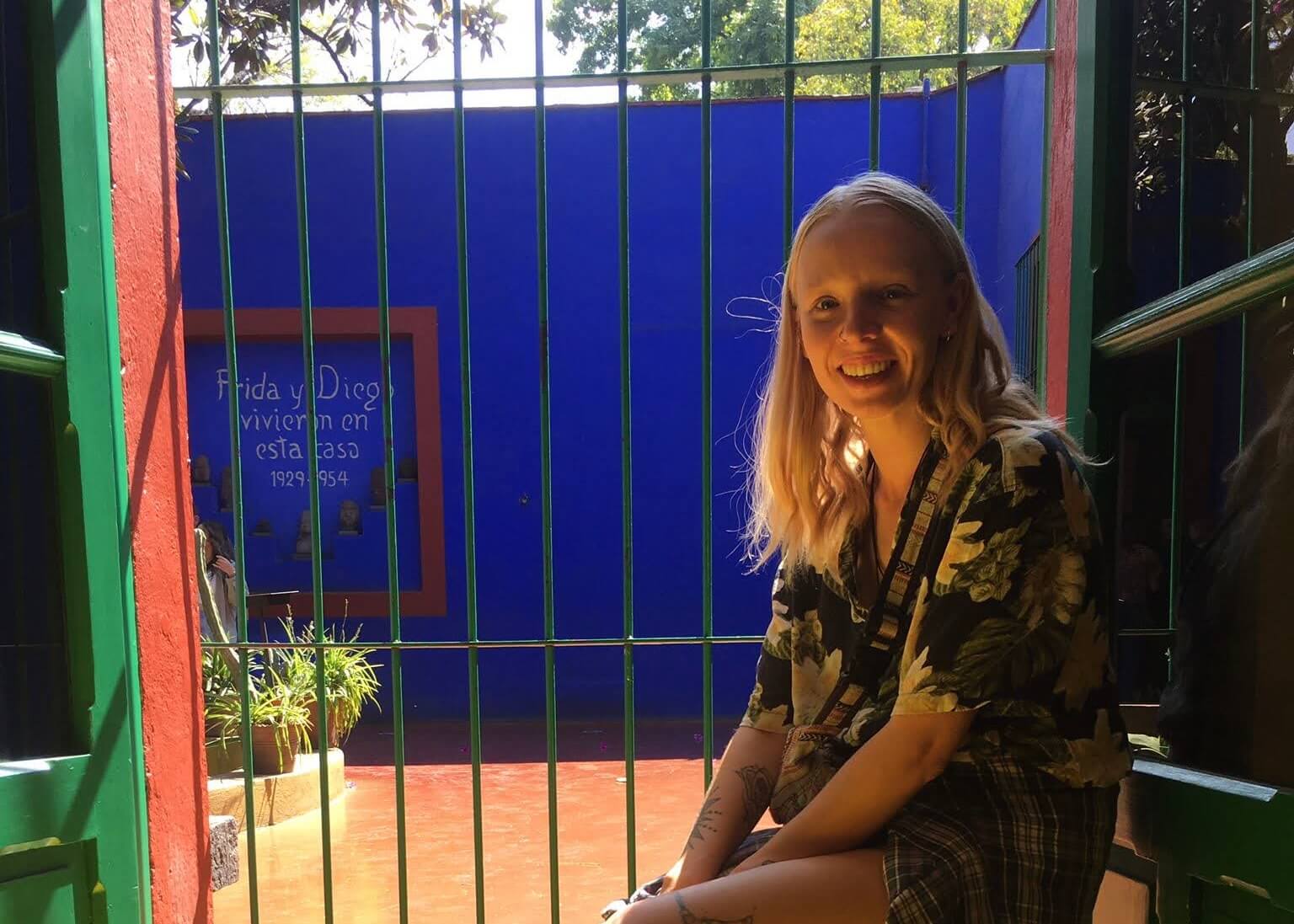 Laura smiling in front of bars on a door in Frida Kahlo's house, Casa Azul in Mexico City