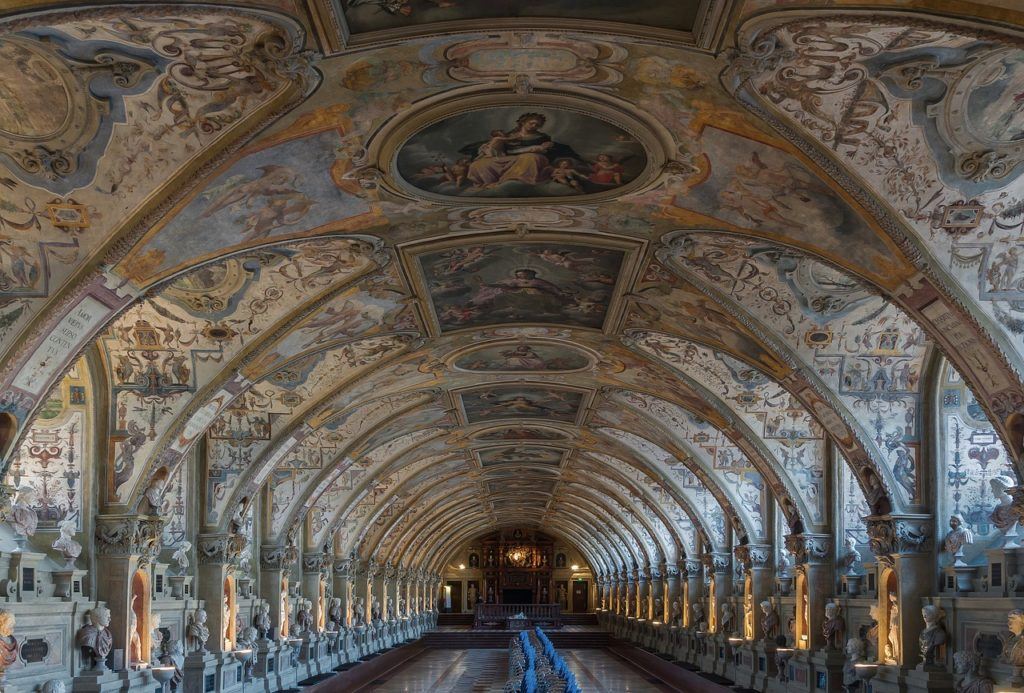 A photo of a long hallway with paintings on the ceiling in Munich Residenz  