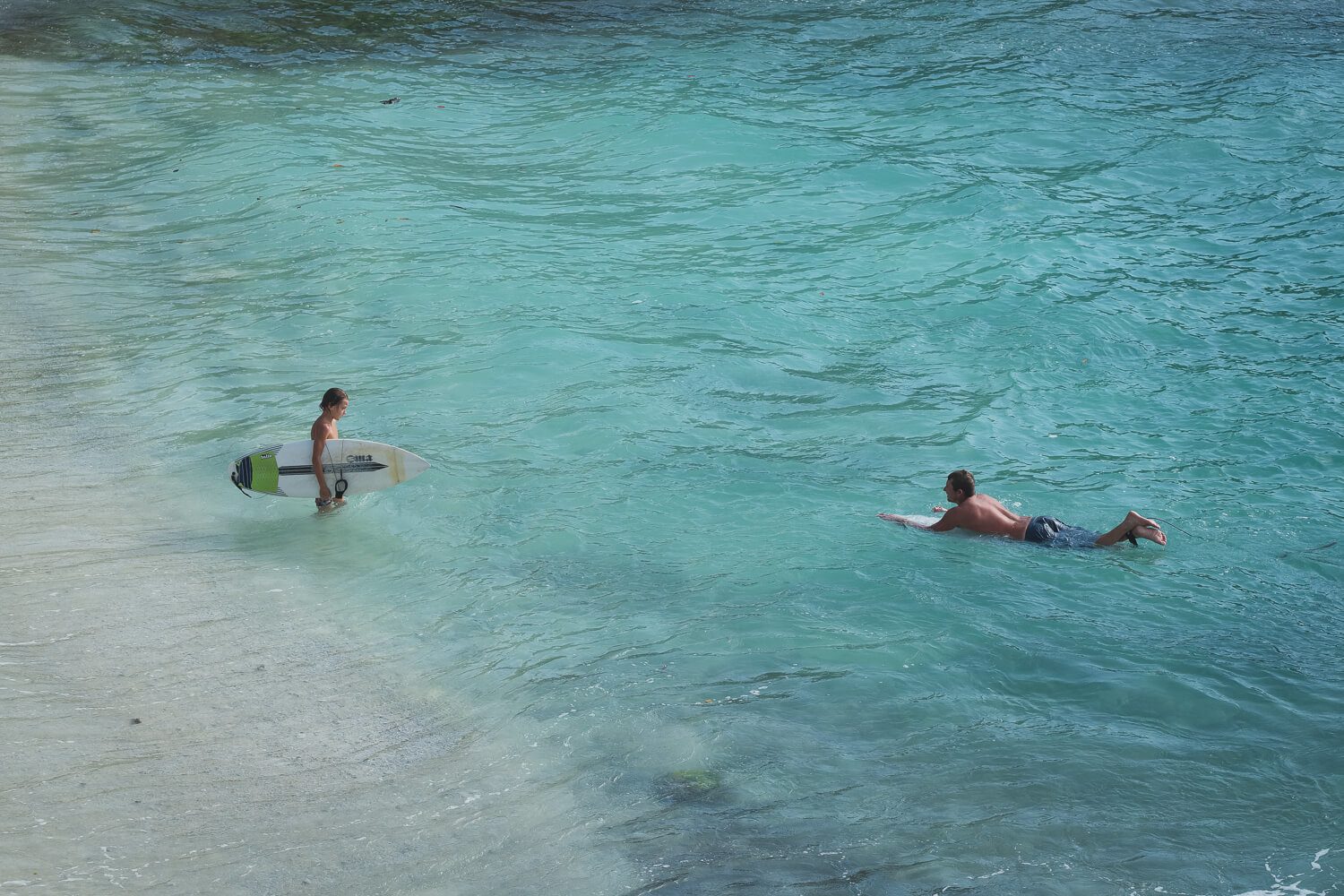 a father and son surfing in turquoise blue waters of nusa lembongan indonesia