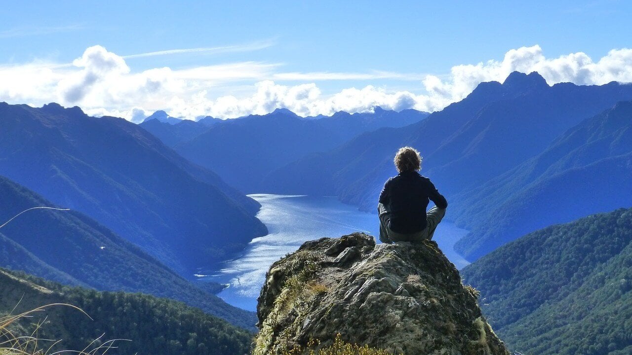 Solo traveller in New Zealand sitting at a viewpoint on the Kepler Track