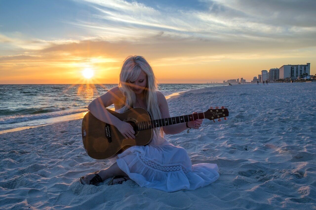 Playing guitar at the beach is a free thing to do in the Sunshine Coast