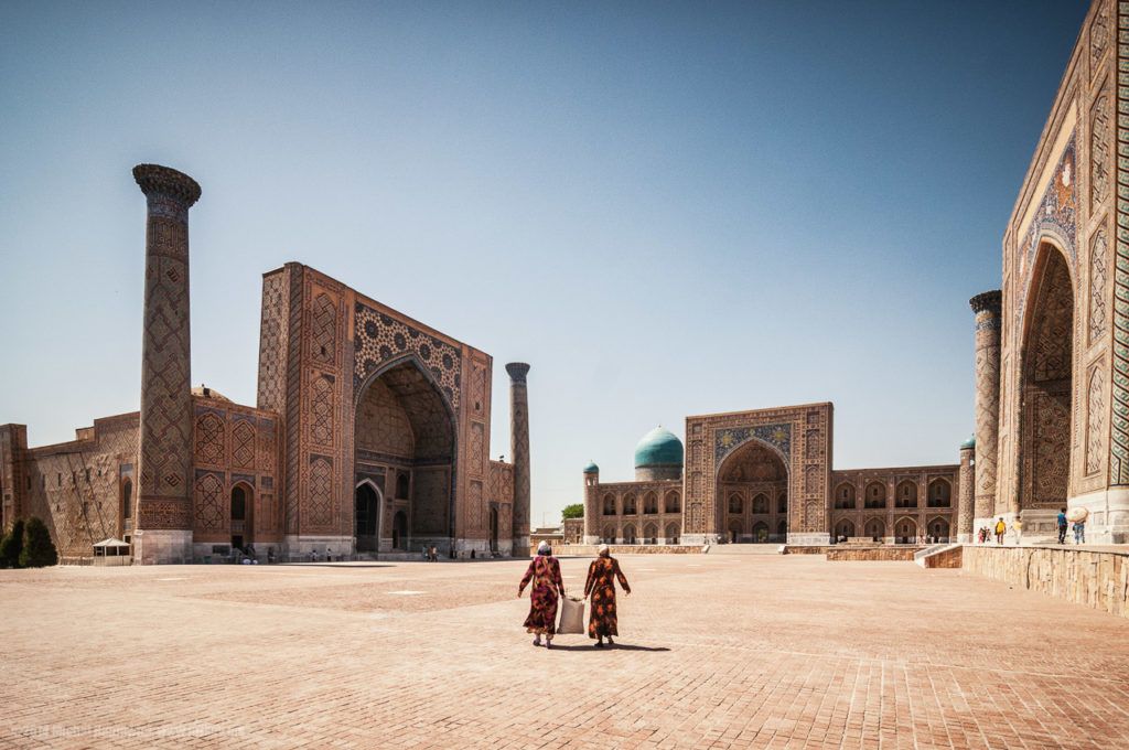 Two women walking in front of buildings in Registan, Samarkand Uzbekistan