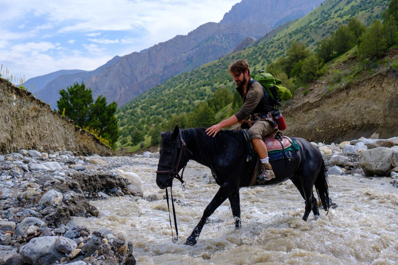 crossing a river while hiking in kyrgyzstan