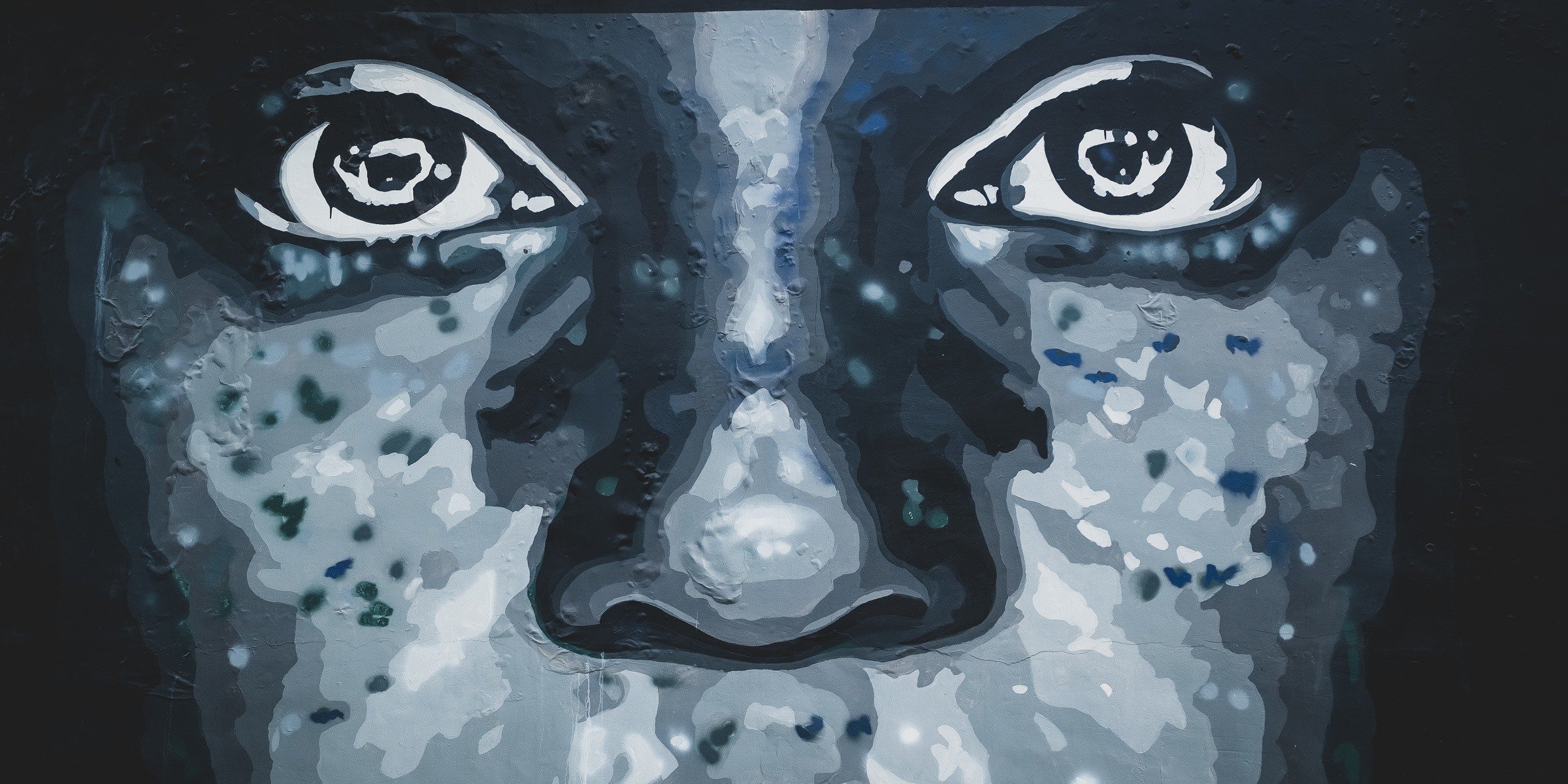 A dimly lit, gradient blue image of a face with a subtle vignette effect on the edges