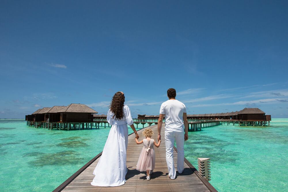 A family visiting a topical beach bungalow resort in Seychelles