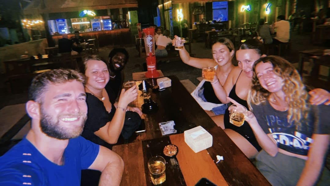 friends posing with a beer tower in a bar in phnom penh, cambodia