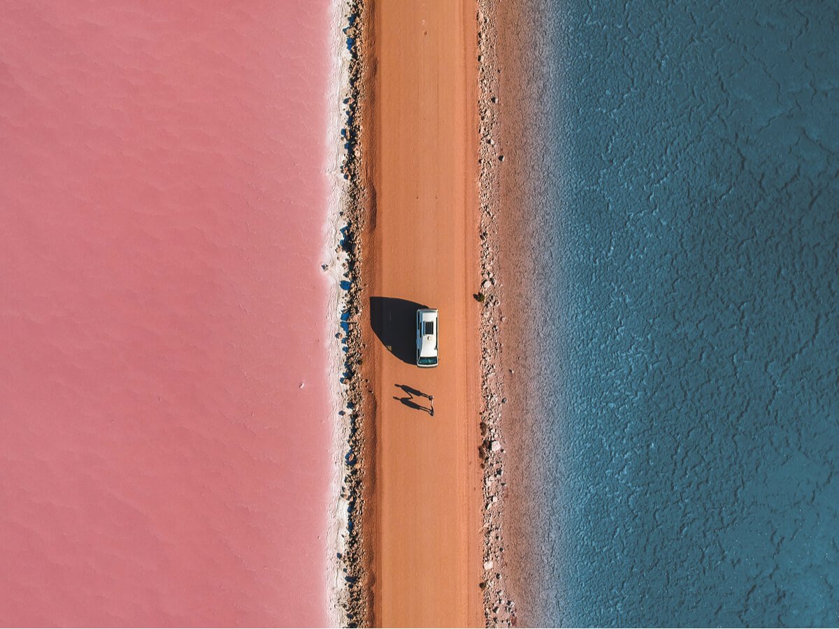 A campervan travelling Australia parked by a salt lake in the Macdonnell Ranges