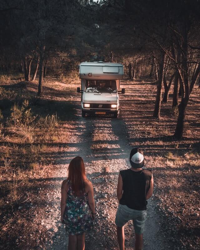 A couple living in a van staring at their motorhome on an empty dirt road