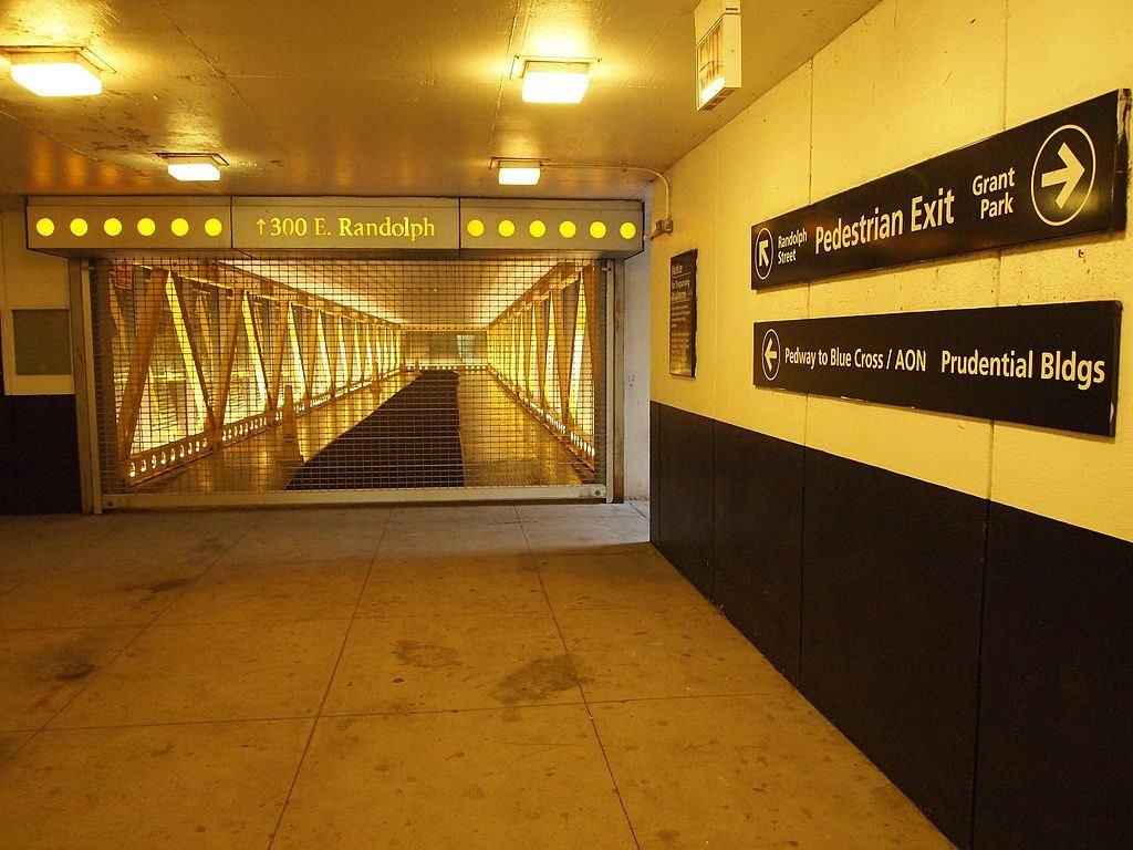 Chicago Pedway with a brick floor and a metal handrail, leading to a brightly lit space. 