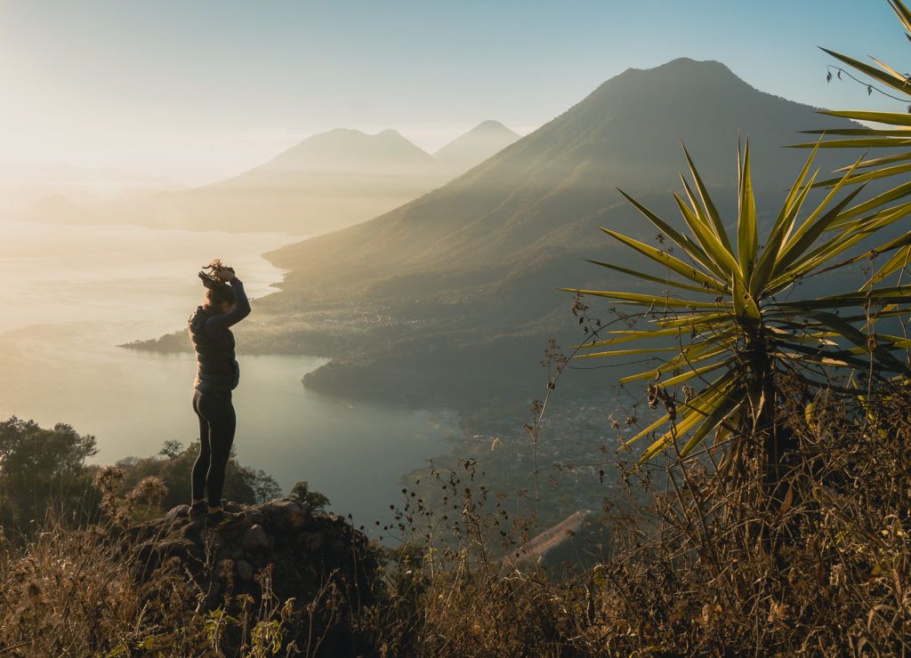 A girl puts her hair into a pony tail on a sunrise hike in French Polynesia