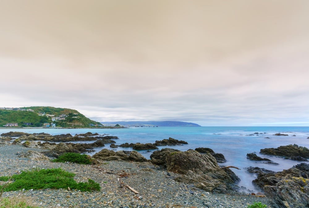 Island bay in Wellington. Roady beach, beautiful blue water and a cloudy sky.