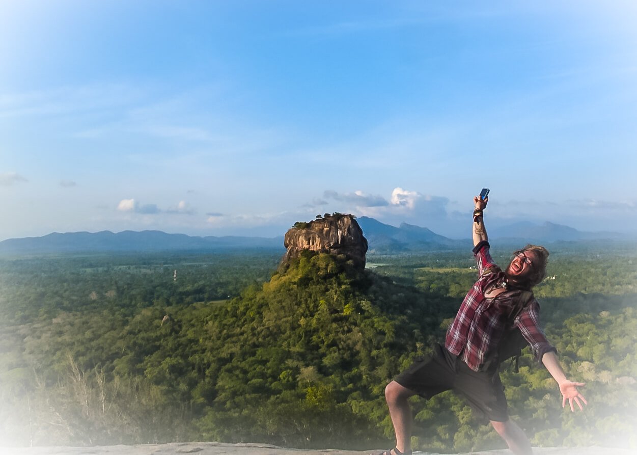 traveller poses for a photo in sri lanka with the Sigiriya rock in the background