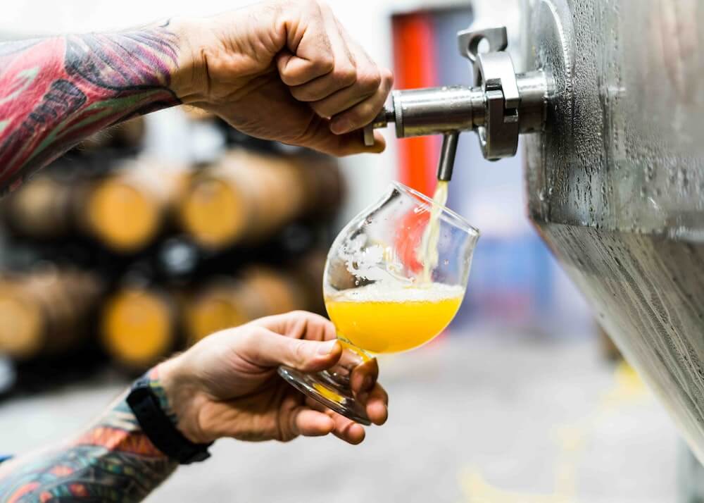 person pouring drink on clear glass during daytime