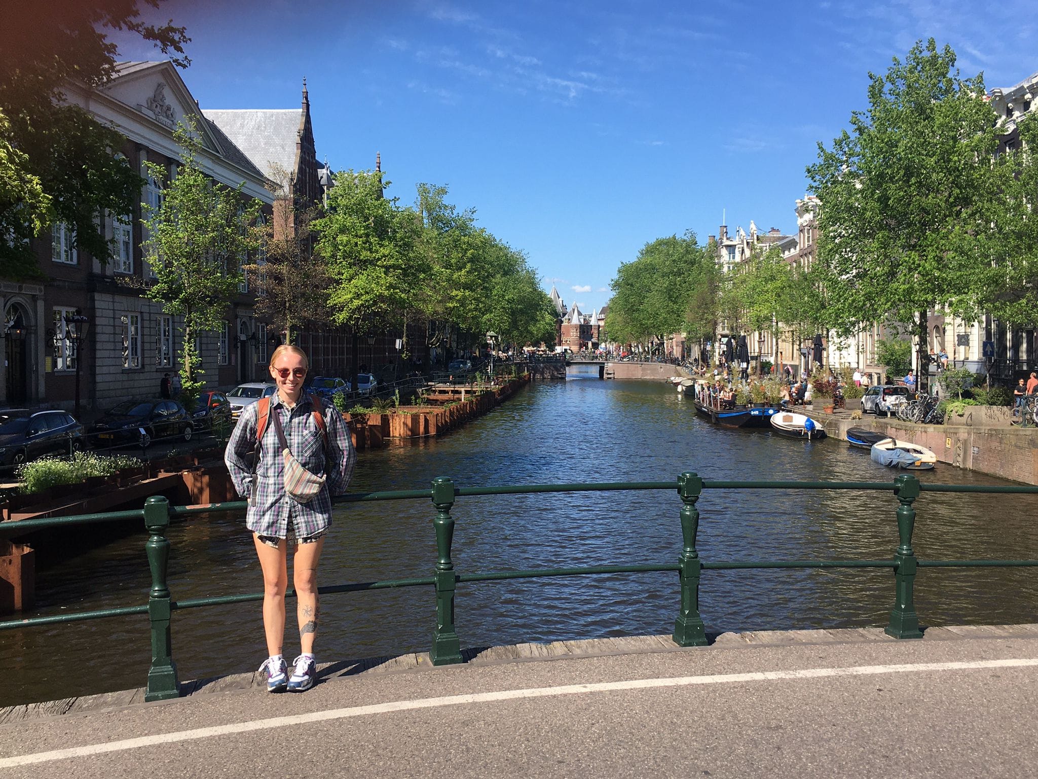 Laura stood smiling on a canal bridge in Amsterdam on a sunny day