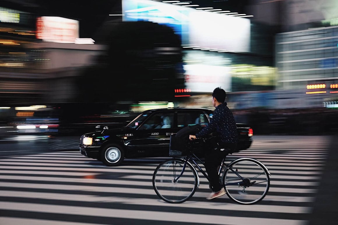 Blurred picture following man on bike crossing zebra crossing in a city at night