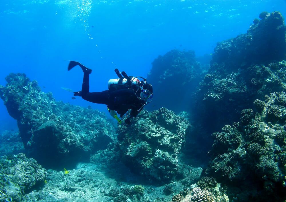 Person scuba diving in Mauritius around boulders