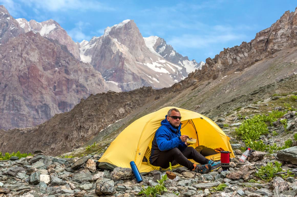 man eating lunch in mountain hike