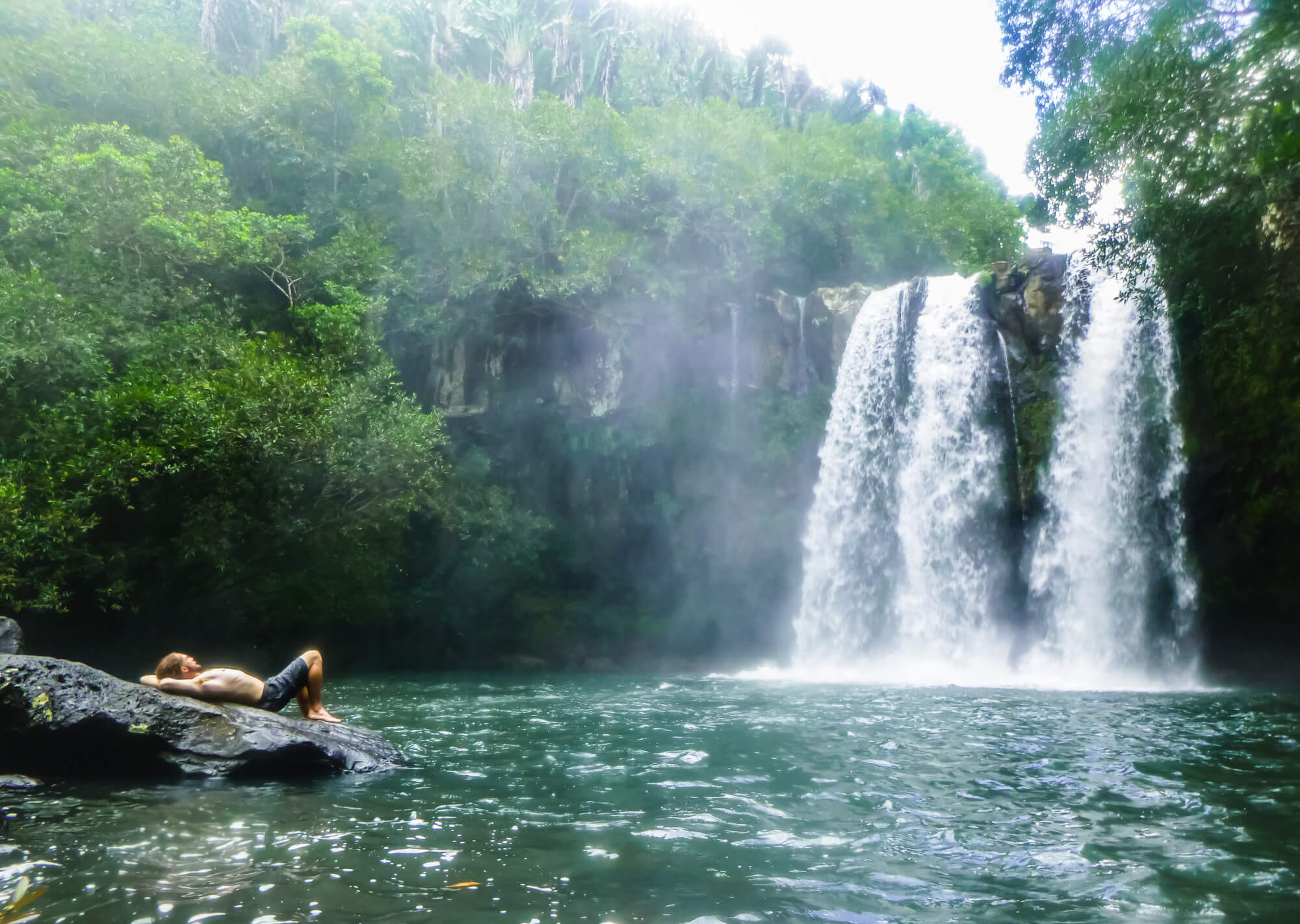 Man takes a break from his diving trip in Mauritius at a waterfall