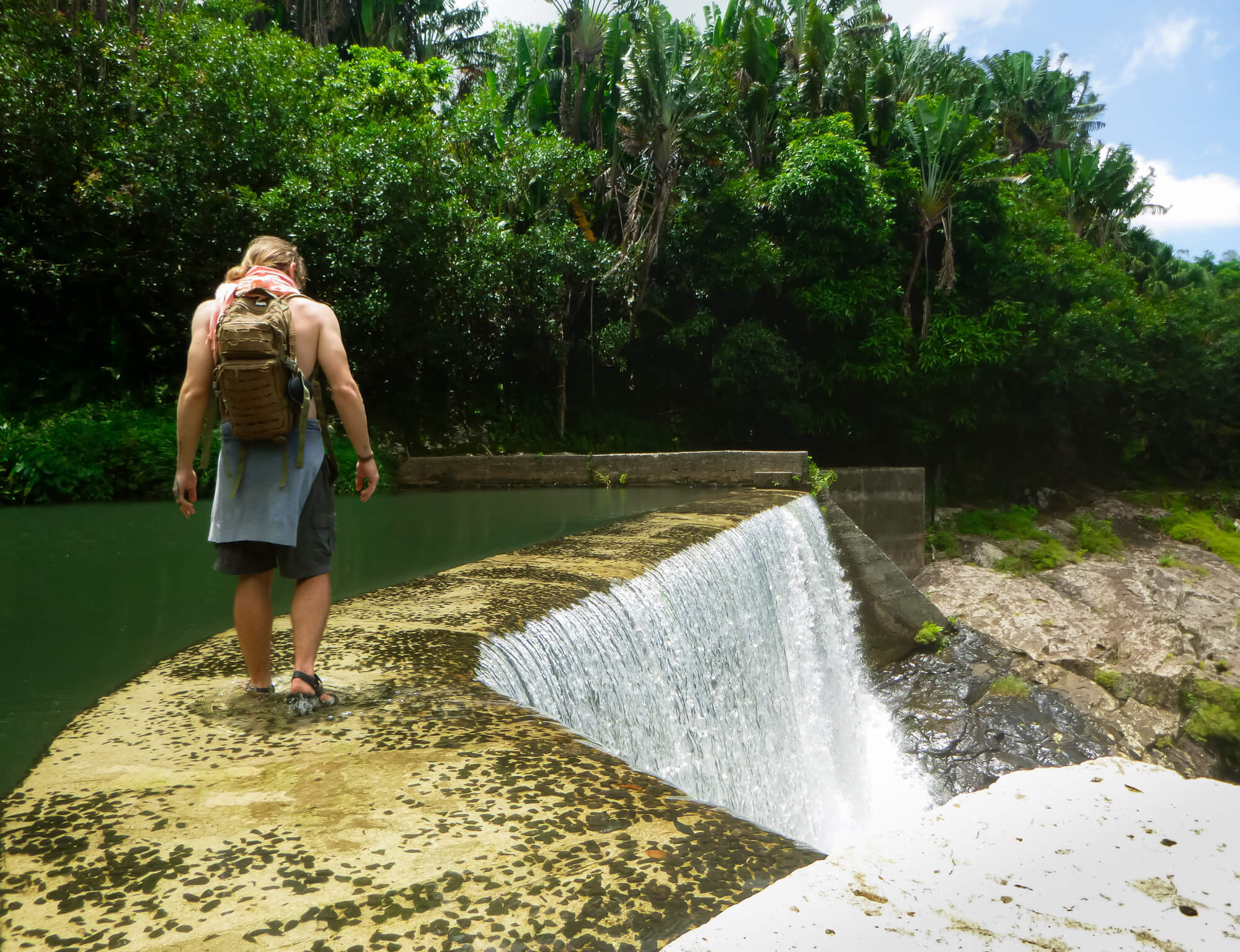 Man hiking in Mauritius across an artificial waterfall