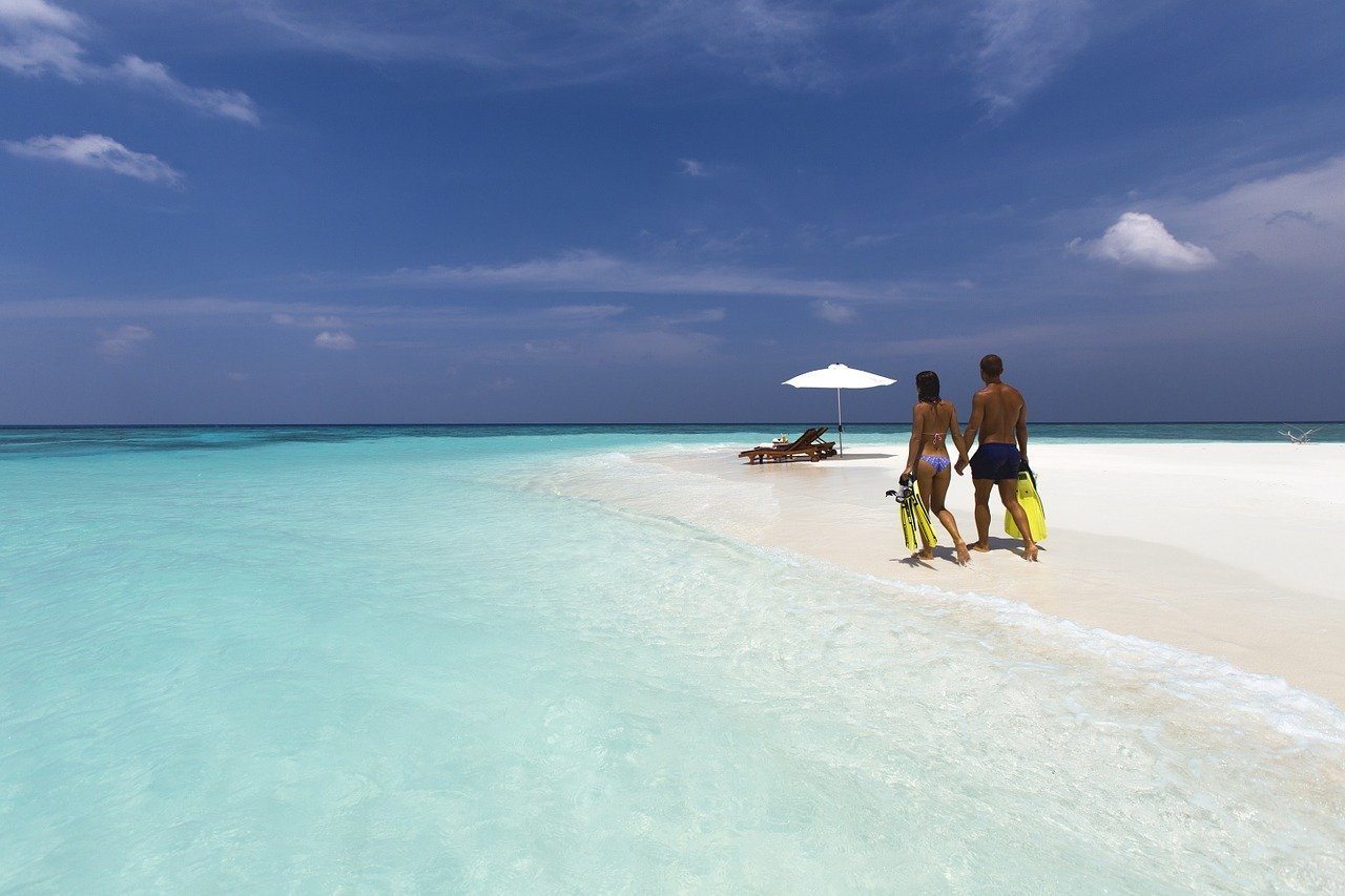 Couple walking on a white beach - best thing to do in Mauritius while on a honeymoon