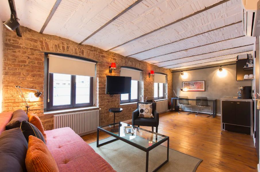 Spacious living room with interior brick walls, wooden floors and a cosy couch.