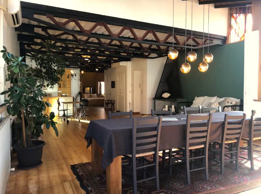 Stylish dining area with a long table with eight seats. Black metal and deep green decor.