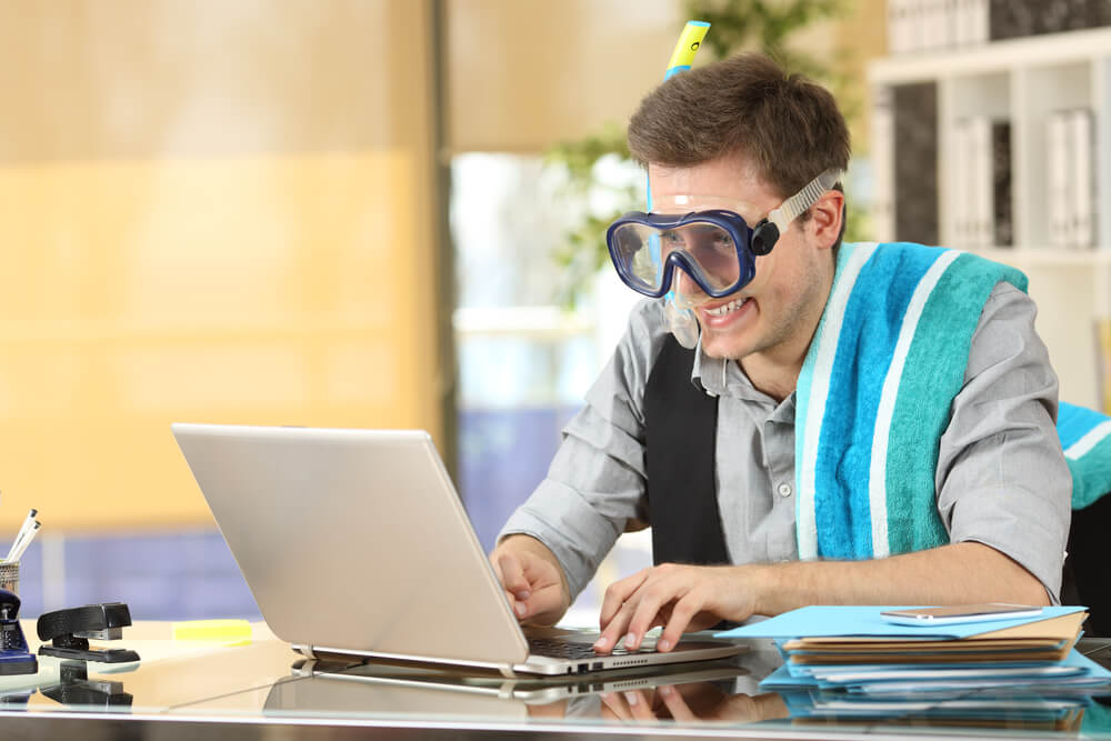 Businessman with safety goggles at a laptop extending his visa for Mauritius