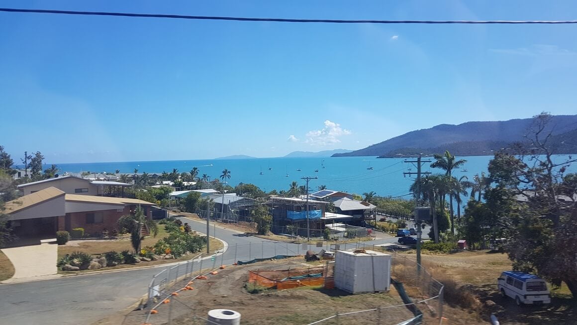 Looking down over part of Airlie Beach town and road on a sunny day with blue skies and sea 