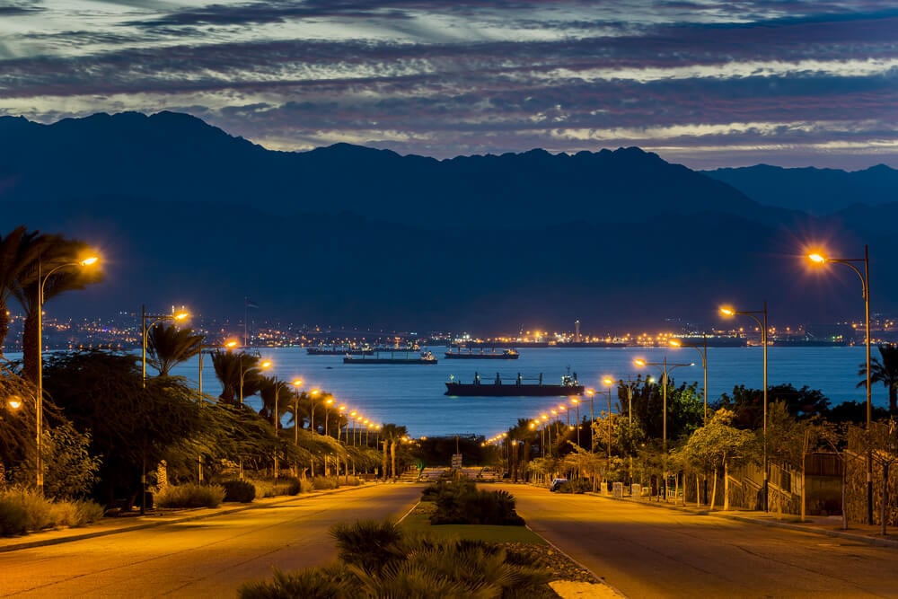 Eilat city and main street at dawn with the Red Sea and Jordanian mountains behind