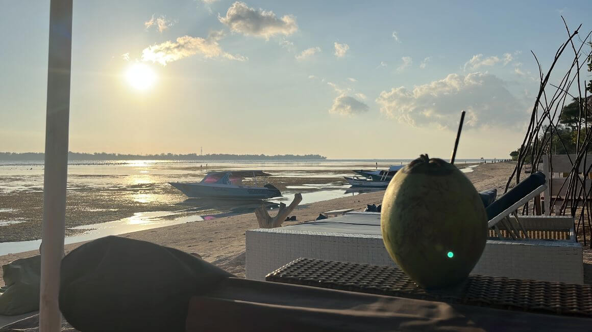 drinking a fresh coconut on the beach in gili air, indonesia