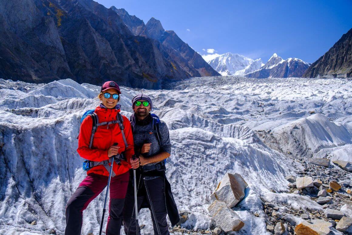 People standing by a glacier in the mountains hiking poles