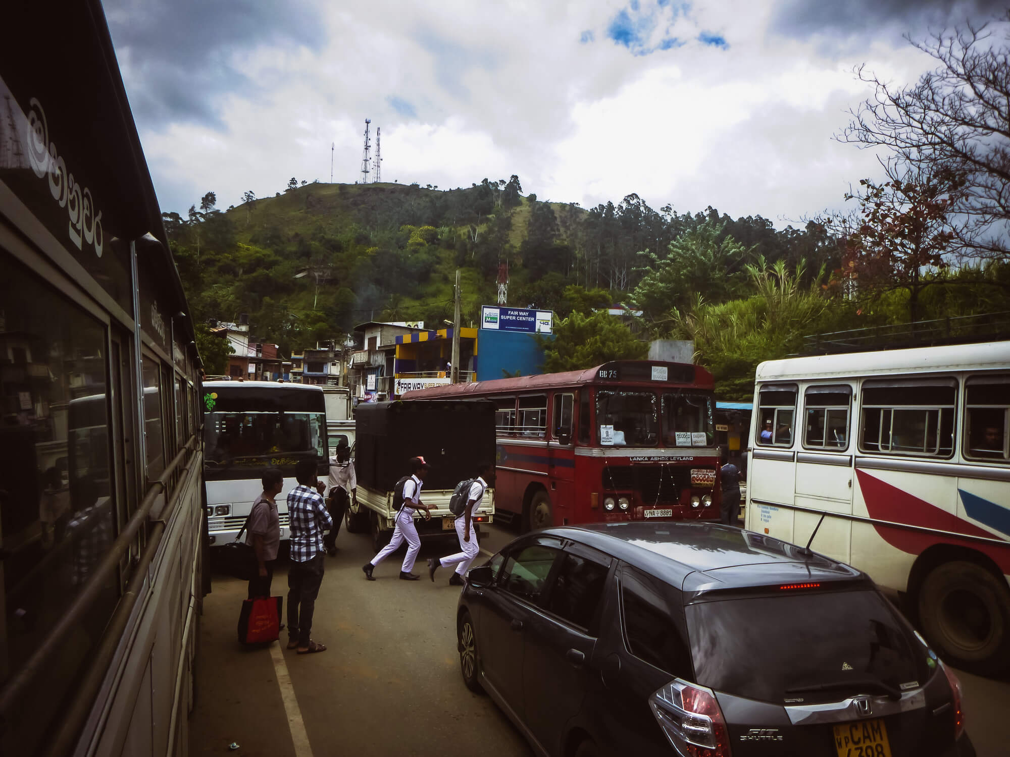 Two boyes in Sri Lanka cross a busy street full of buses