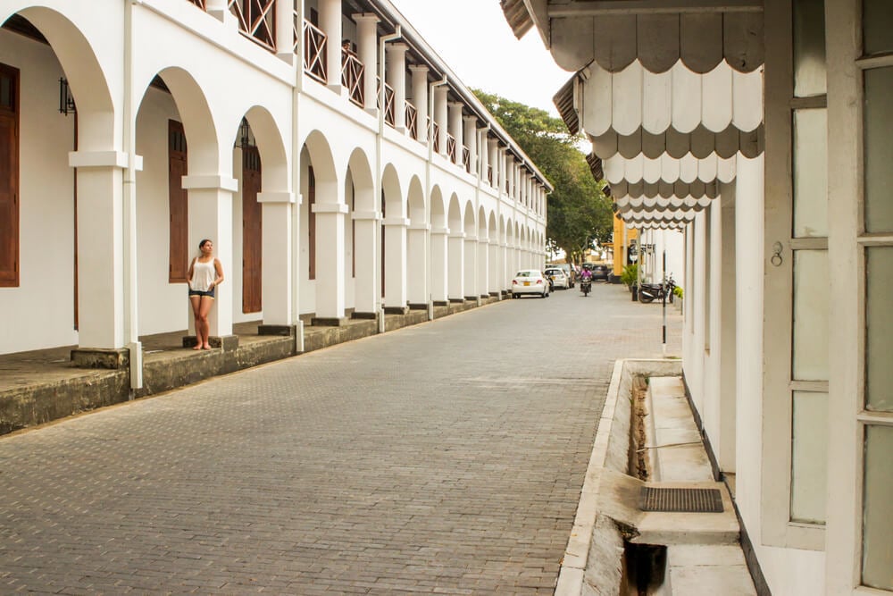 Backpacker in the tourist destination  Galle Fort poses against a white building