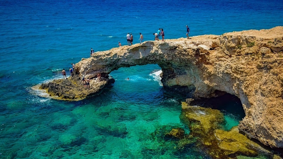 people standing on a limestone cliff in the shape of a small bridge in Ayia Napa, Cyprus