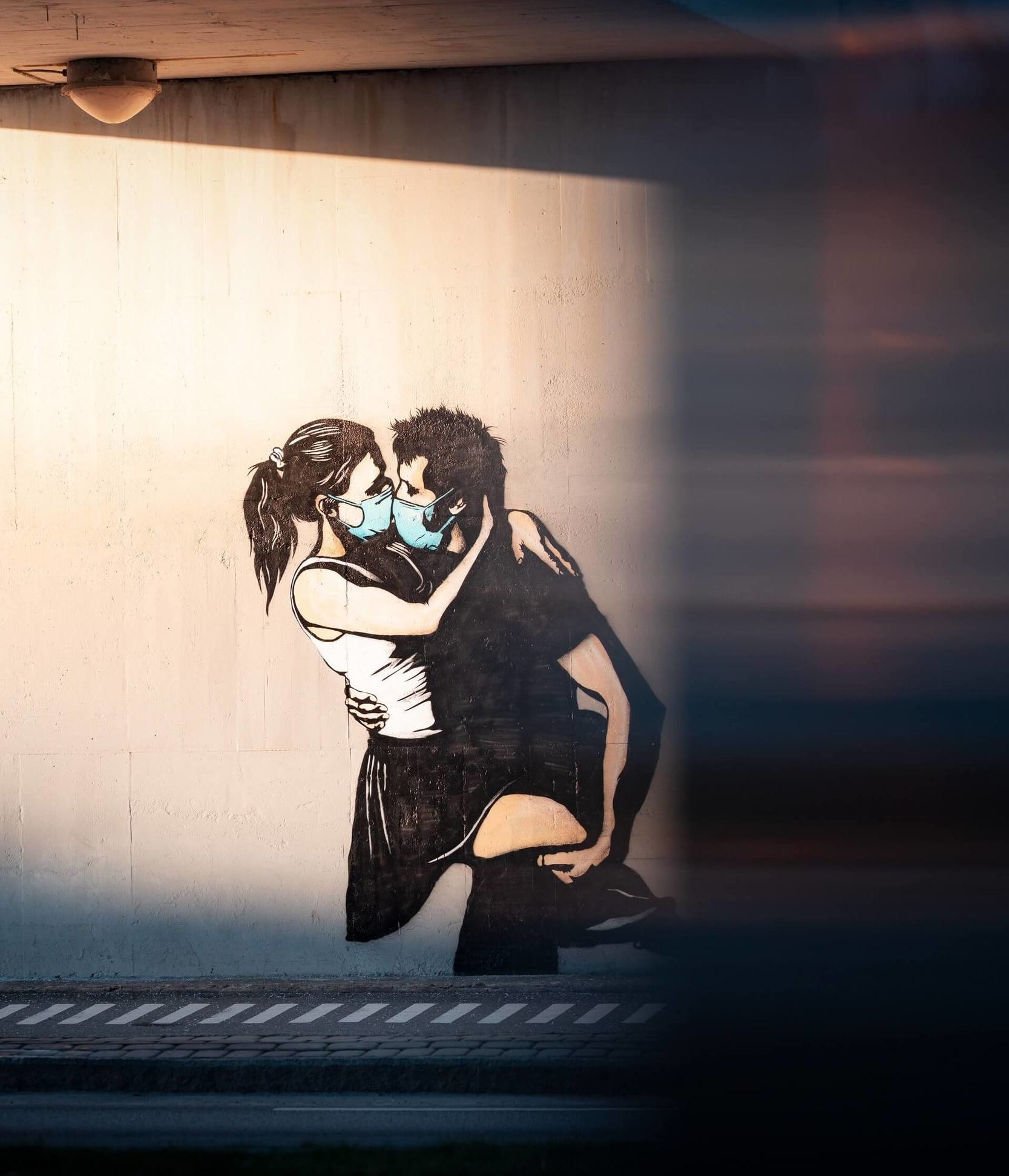 Street art of two peopl "kissing" during COVID