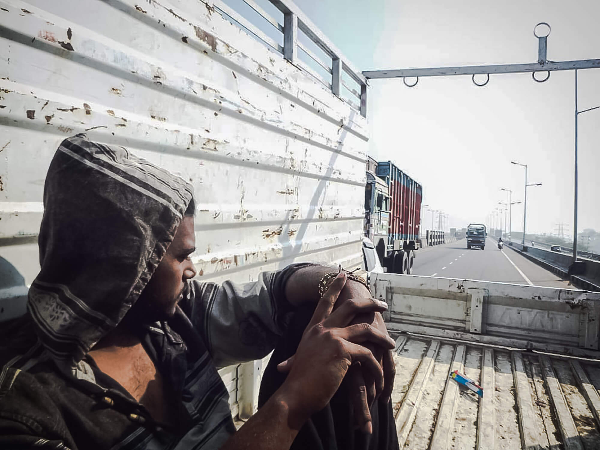 A man rides in a truck after finding a travel partner to hitchhike India with