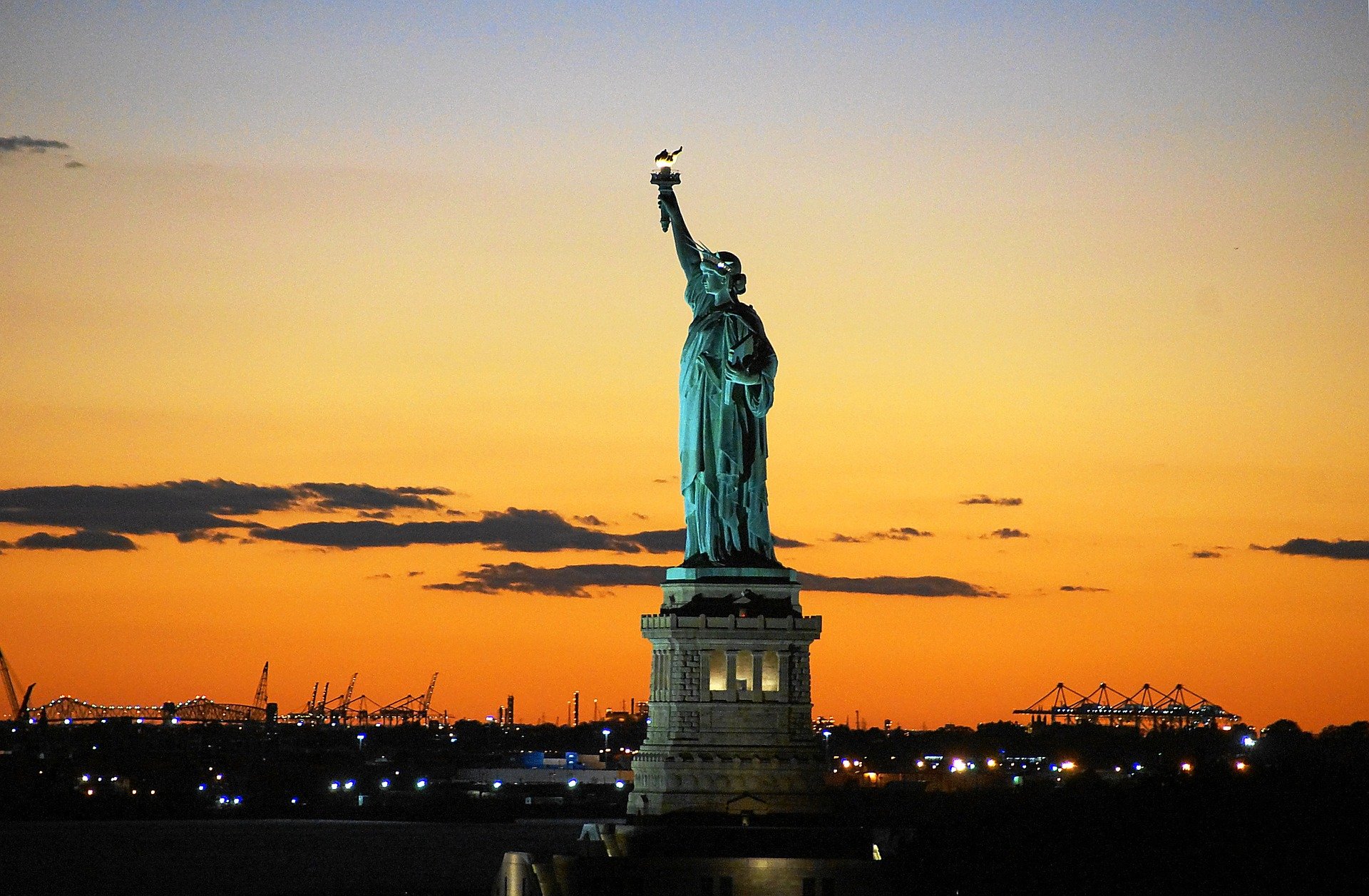 statue of liberty set against an orange sunset backpacking USA